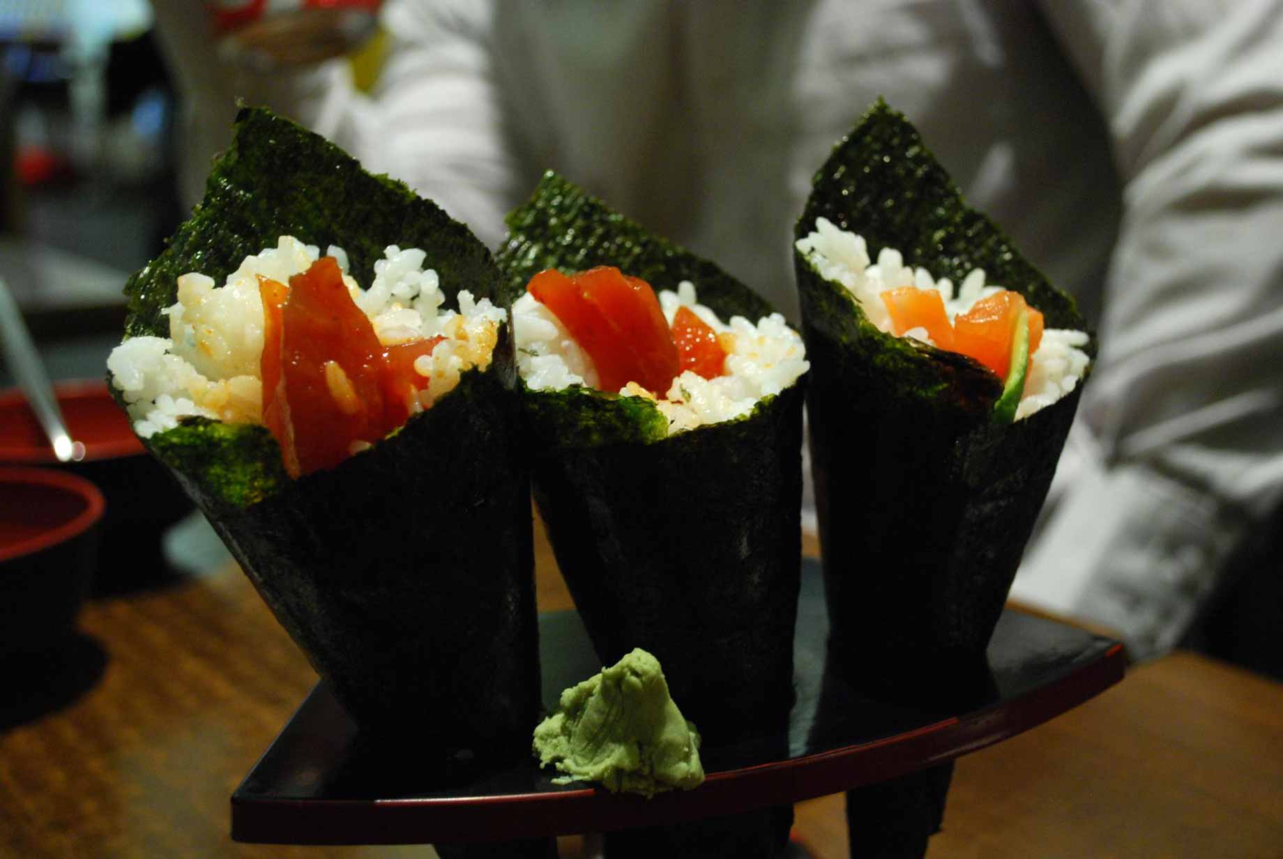 temaki-sushis, riz vinaigre, poisson cru et légumes entourés d'une feuille d'algue nori